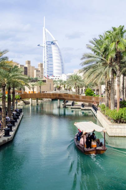 Dubai, United Arab Emirates - November 21, 2019: Abras are traditional boats in Dubai. Here it's transporting people through a canal. The view of Burj Al Arab in the background sets the tone to this luxurious city.