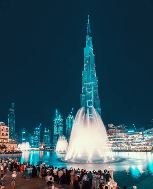  UAE, Dubai: Evening view of the illuminated tower of Burj Khalifa and a pond with a dancing fountain. Popular and majestic show in Dubai