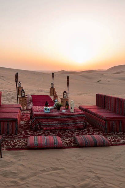 Desert dinner set up for sunset romantic meal at sand dunes with carpets and cushions