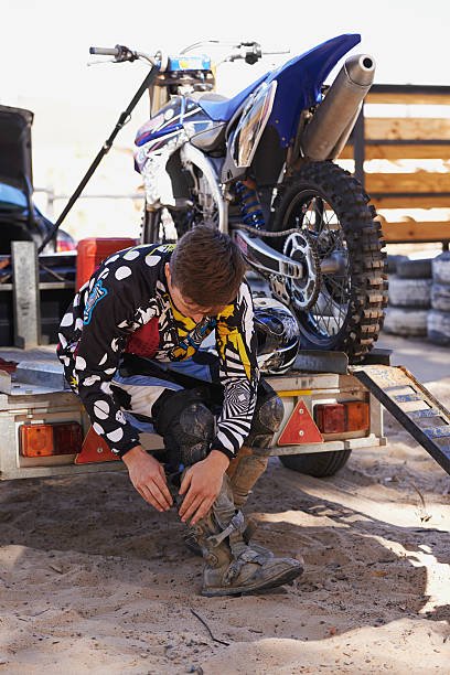 Full length shot of a dirt bike rider putting on his protective bootshttp://195.154.178.81/DATA/i_collage/pi/shoots/783228.jpg