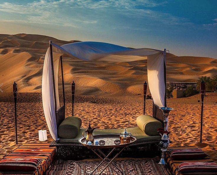  A cozy tent with cushions and a table set up in the desert for Desert Safari and BBQ.