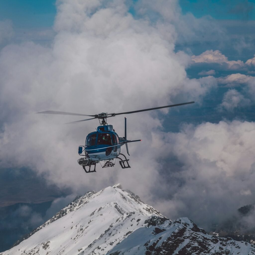 A helicopter soaring over Dubai's mountain range with clouds in the background.