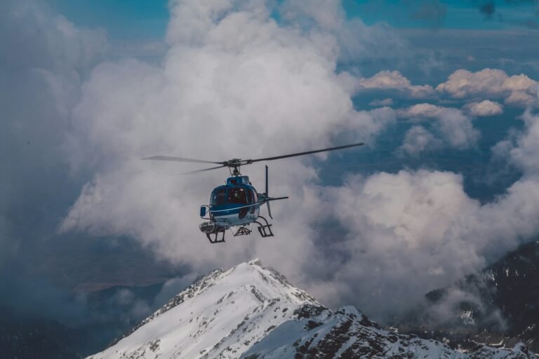 A helicopter soaring over Dubai's mountain range with clouds in the background.