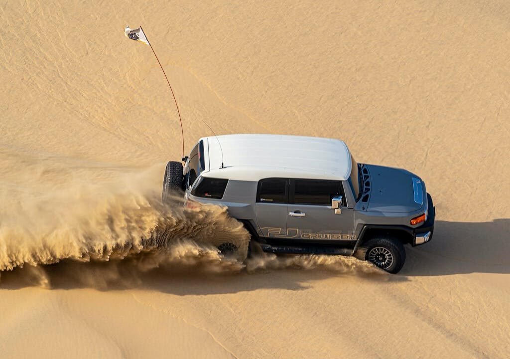 A jeep driving through the sandy desert in Dubai.