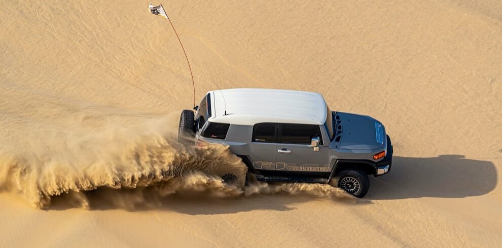 A jeep driving through the sandy desert in Dubai.