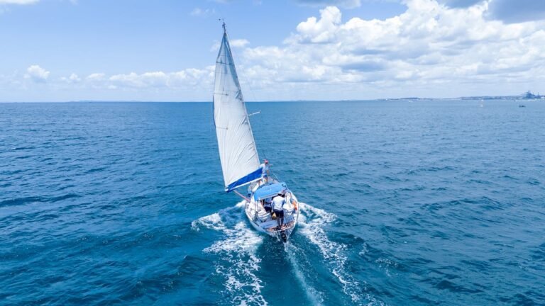 A yacht sailing in the ocean with the city of Dubai in the distance.