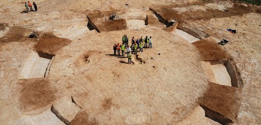 People gathered around circular Bronze Age Burial Mounds.
