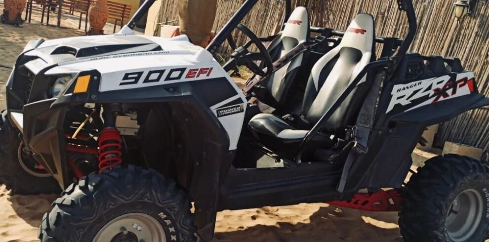 Off-road two seater dung with black tires in Dubai's sandy terrain.