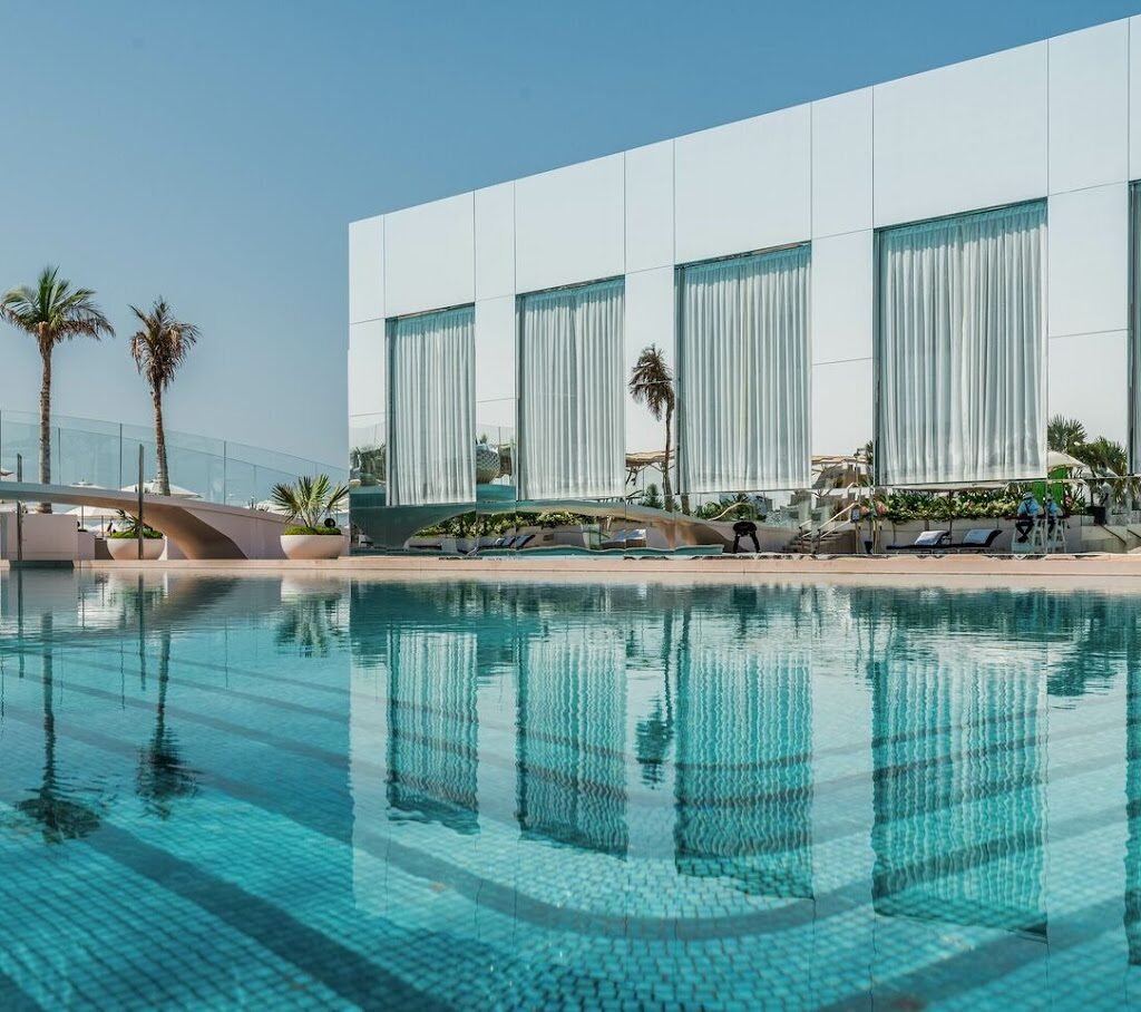 A pool in front of the white-walled Burj Al Arab building.