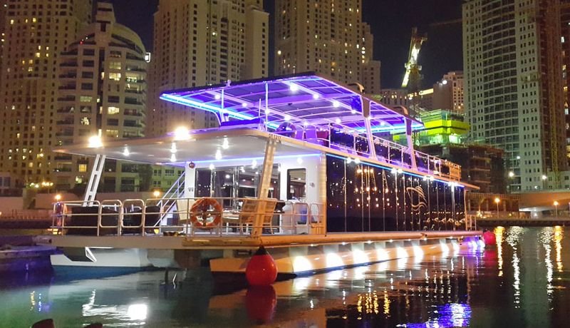 Dubai Canal Cruise diner: boat docked in city at night.

