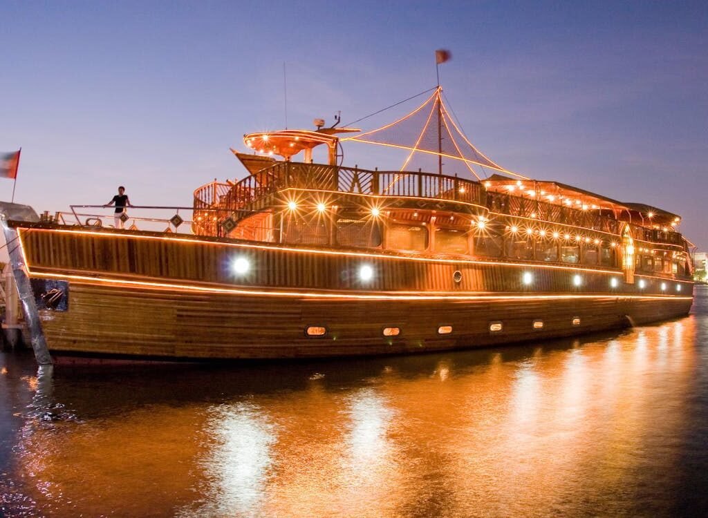 A large boat docked at night in a harbor, Dubai Creek Dhow Dinner Cruise.