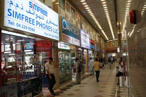  A bustling shopping mall with numerous people walking around, located in Dubai's Electronics Souk.
