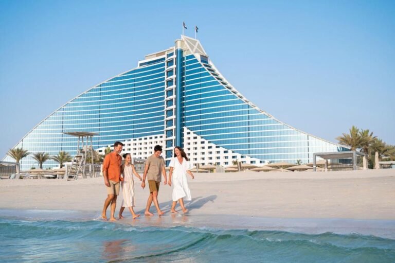 Family leisurely walking by Burj Al Arab hotel on Jumeirah Beach.