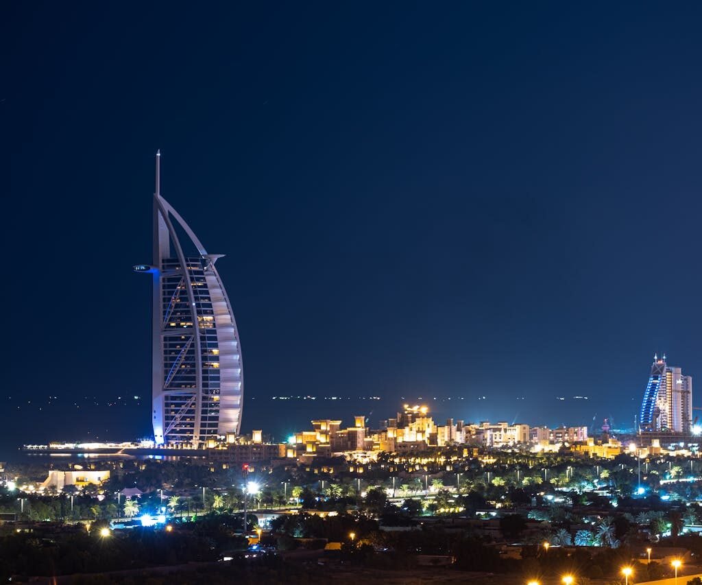 Night view of Burj Al Arab hotel in Dubai, illuminated against the dark sky.