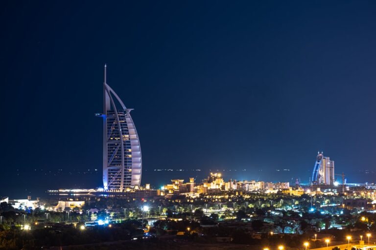 Night view of Burj Al Arab hotel in Dubai, illuminated against the dark sky.