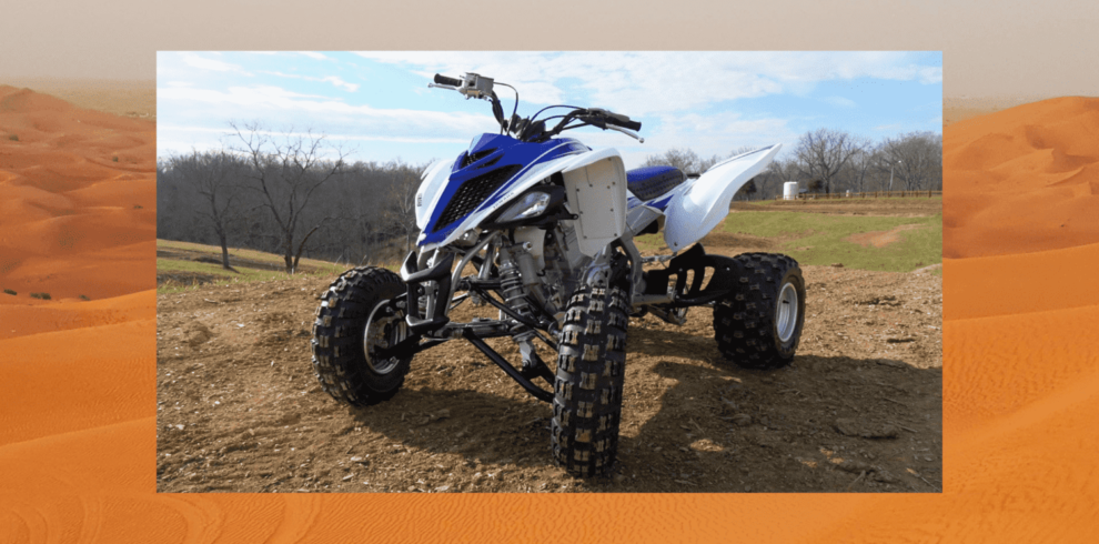 White and blue quad bike on sandy field in Dubai.