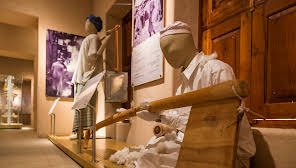 Mannequins in Sharjah Heritage Museum with a wooden bench.