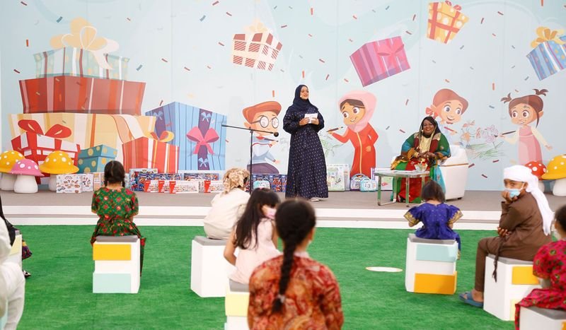 Children and woman in hijab on stage, part of 'Stories Behind Sharjah's Heritage