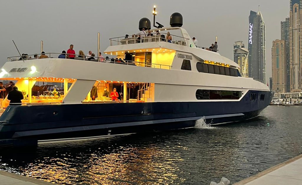 A large yacht docked at the dock with people on board during a Sunset Dinner Cruise in Dubai.