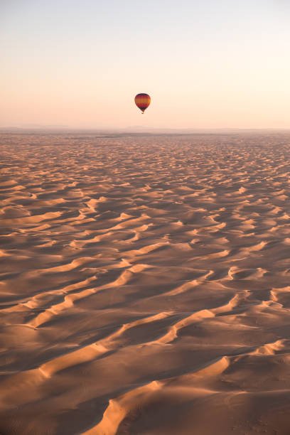 Colorful air balloons flying during dawn over desert dunes. Dubai, UAE.