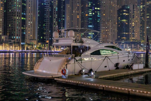 Dubai, United Arab Emirates, March 16, 2023 : Night view from the promenade of Dubai Marina with illuminated skyscrapers, a water channel, yachts and ships in Dubai city, United Arab Emirates