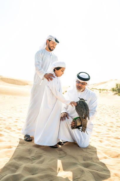 Three generation family making a safari in the desert of Dubai. Grandfather, son and grandson spending time together in the nature and training their falcon bird.