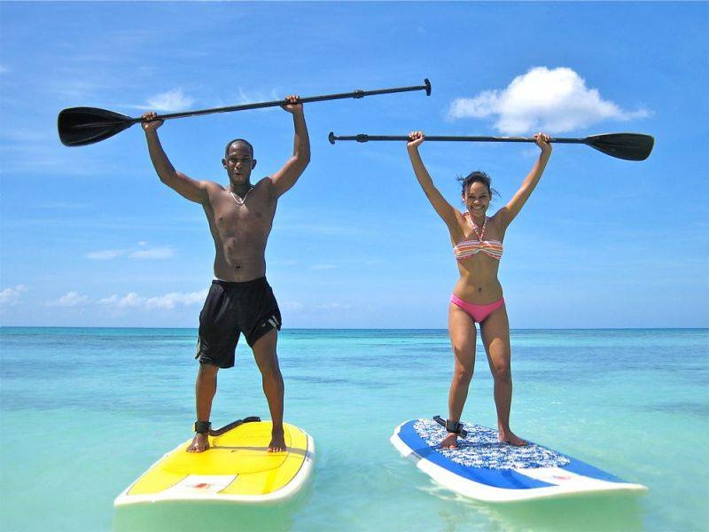 A couple enjoying paddleboarding in the ocean.