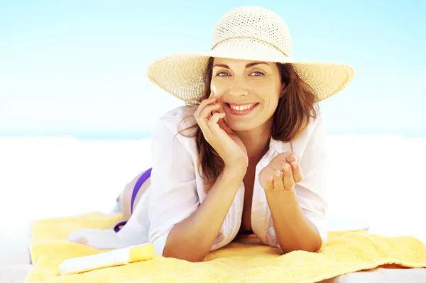 Summer vibes with woman in hat and white shirt on towel,